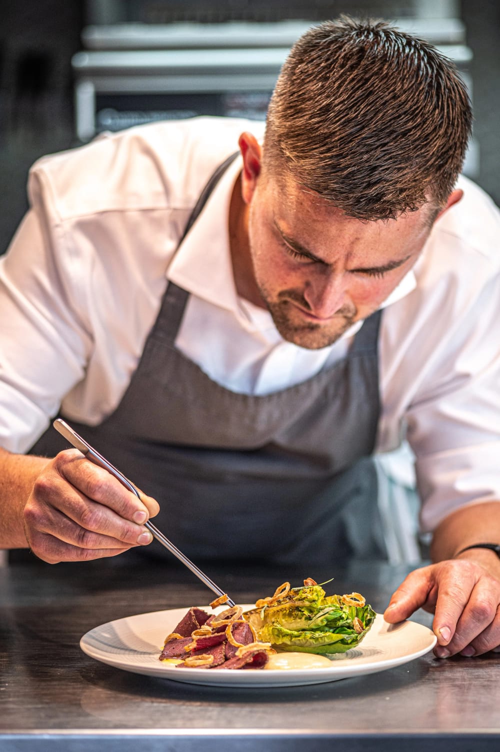 A chef plating a dish in the YouBeChef kitchen