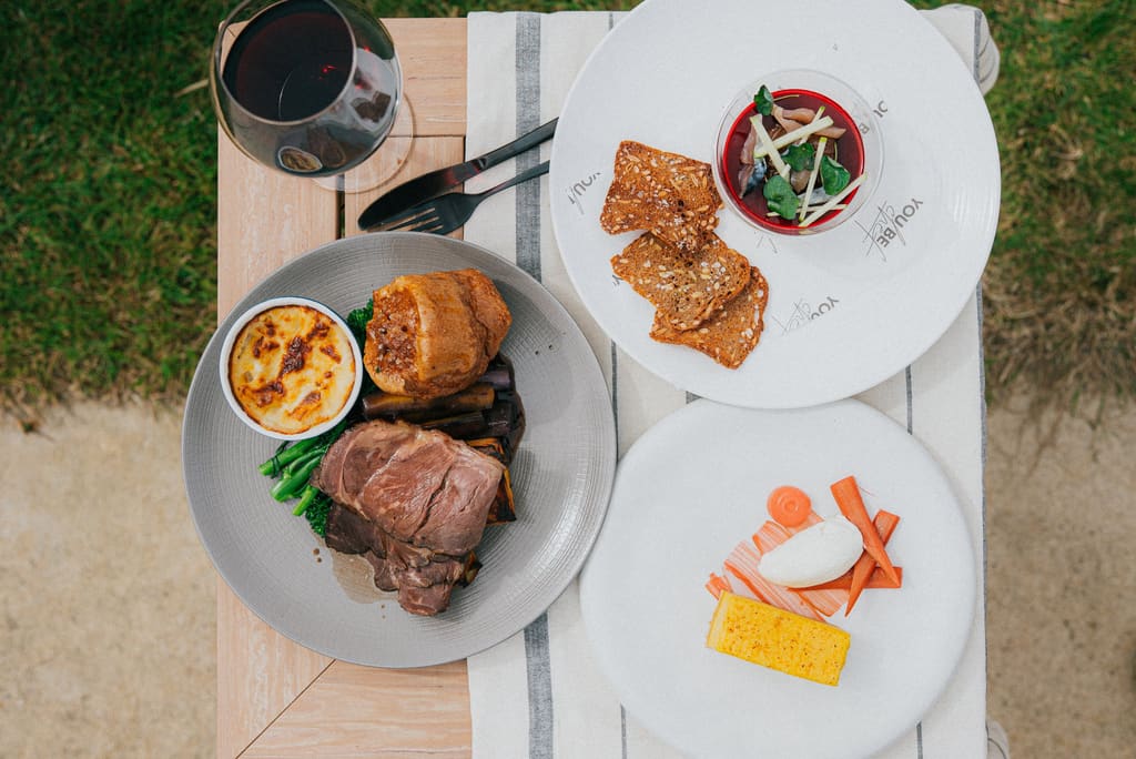 A YouBeChef menu plated at home on a striped linen cloth, with a glass of red wine